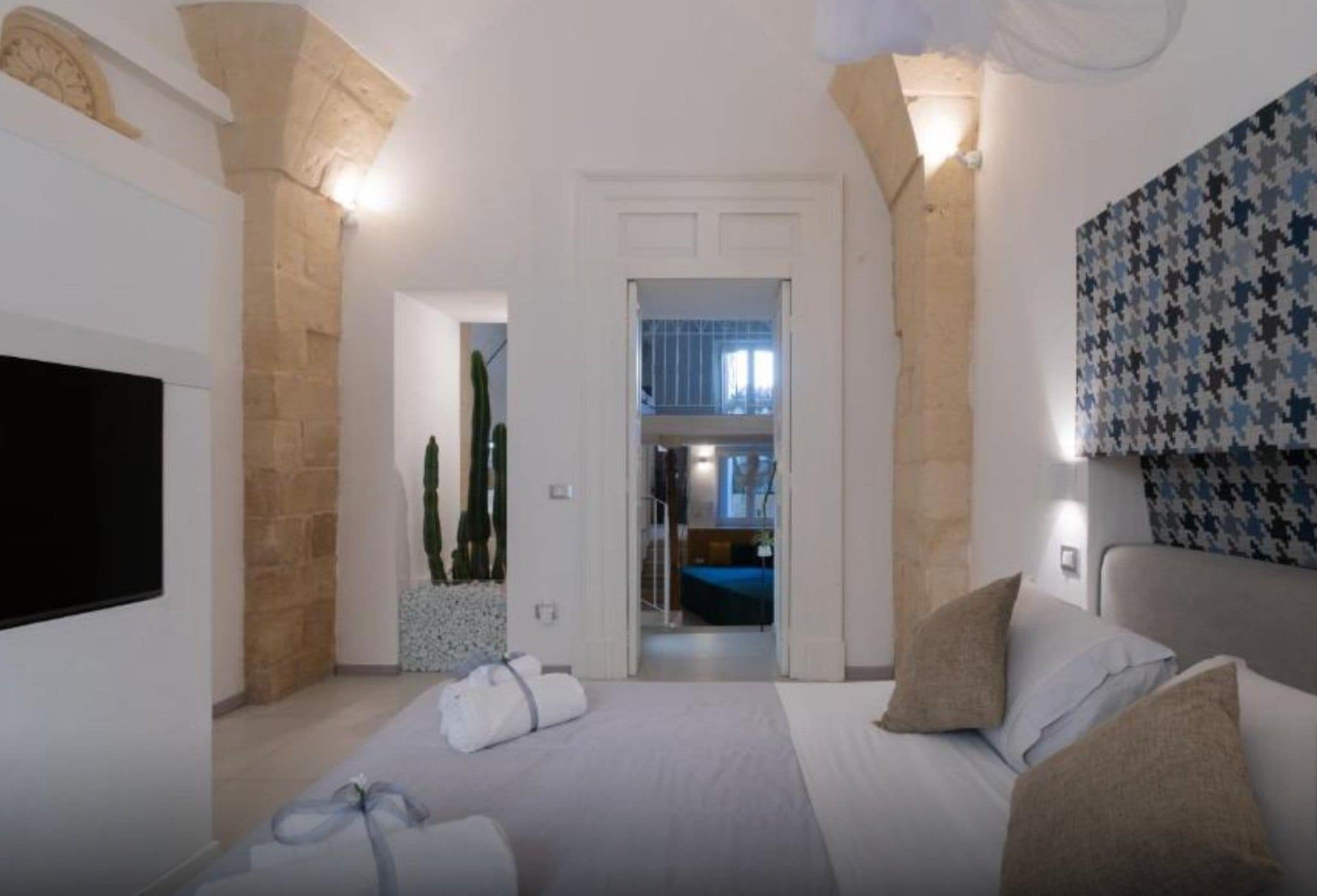 Une chambre à coucher moderne avec un lit, des oreillers, un téléviseur à écran plat et une vue sur un balcon.