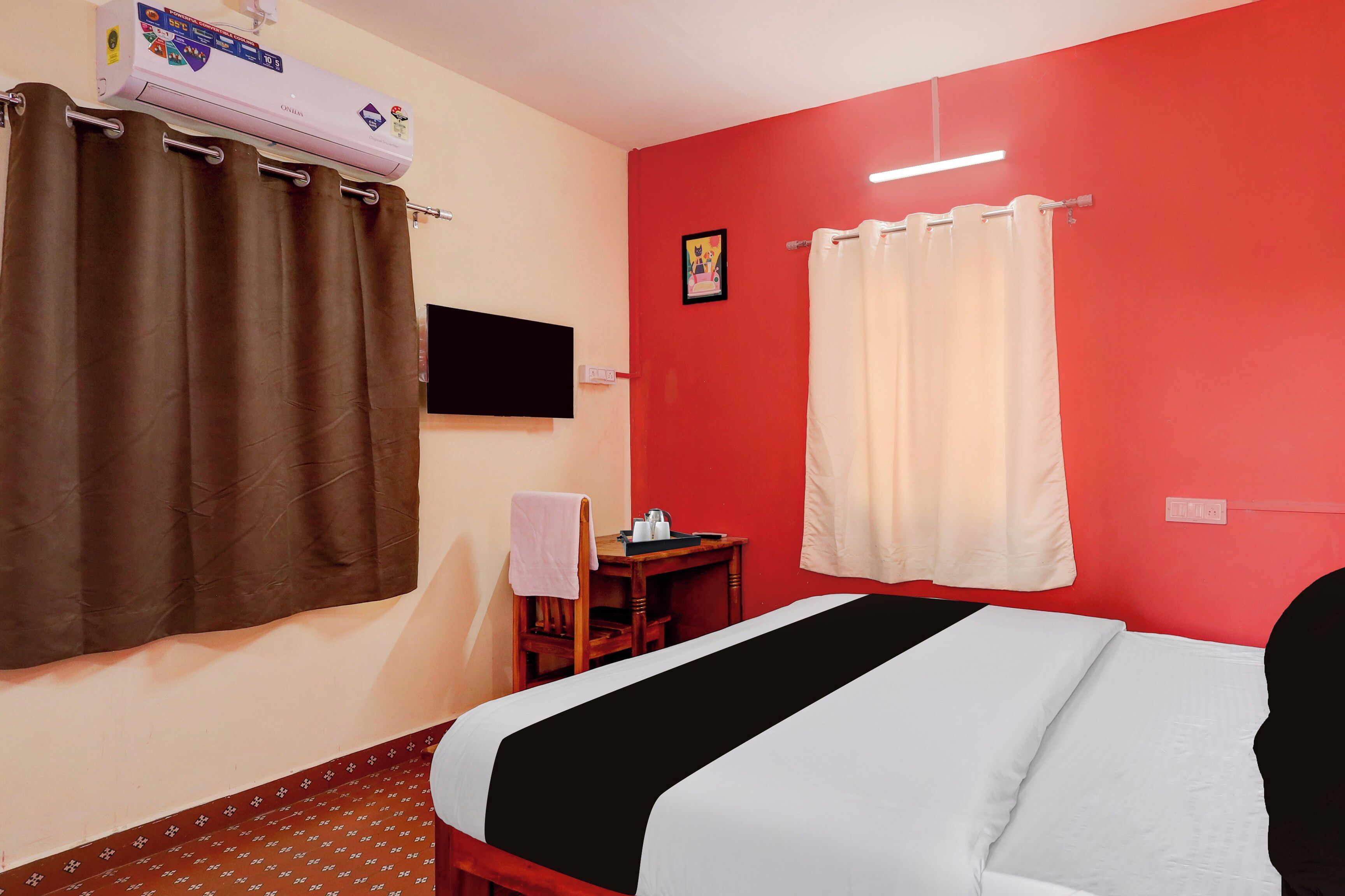 A hotel room with a bed, a desk, a chair, a TV, and a window with curtains.