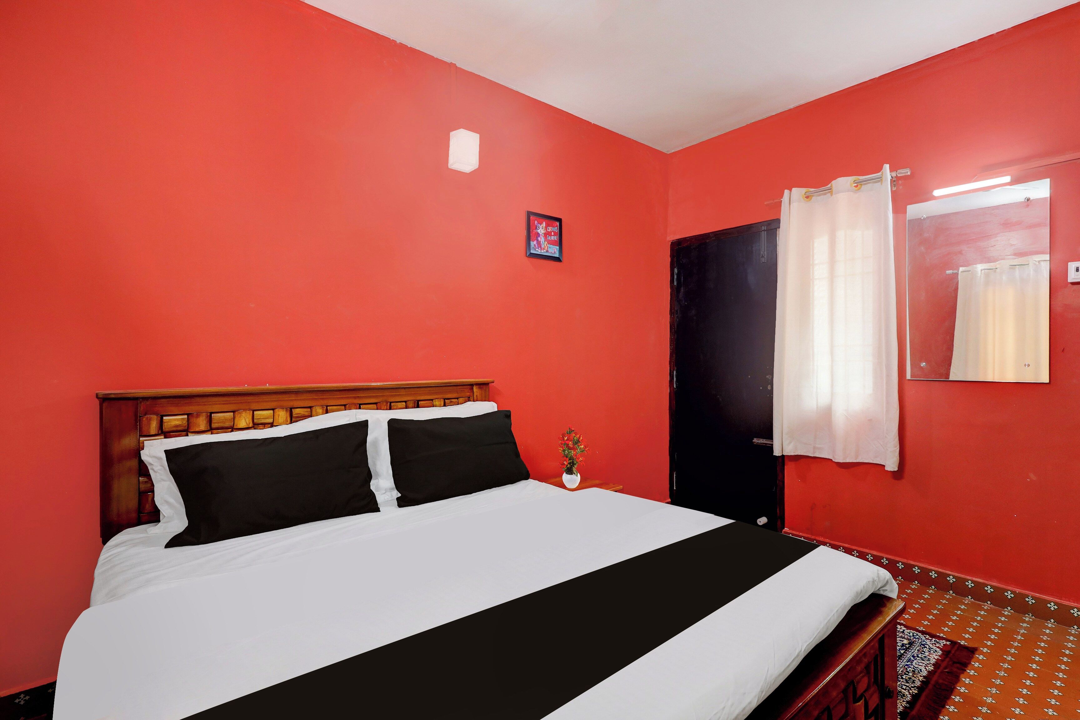 Quarto com uma cama, uma porta e uma parede com um quadro.