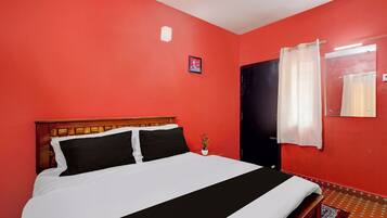 Quarto com uma cama, uma porta e uma parede com um quadro.