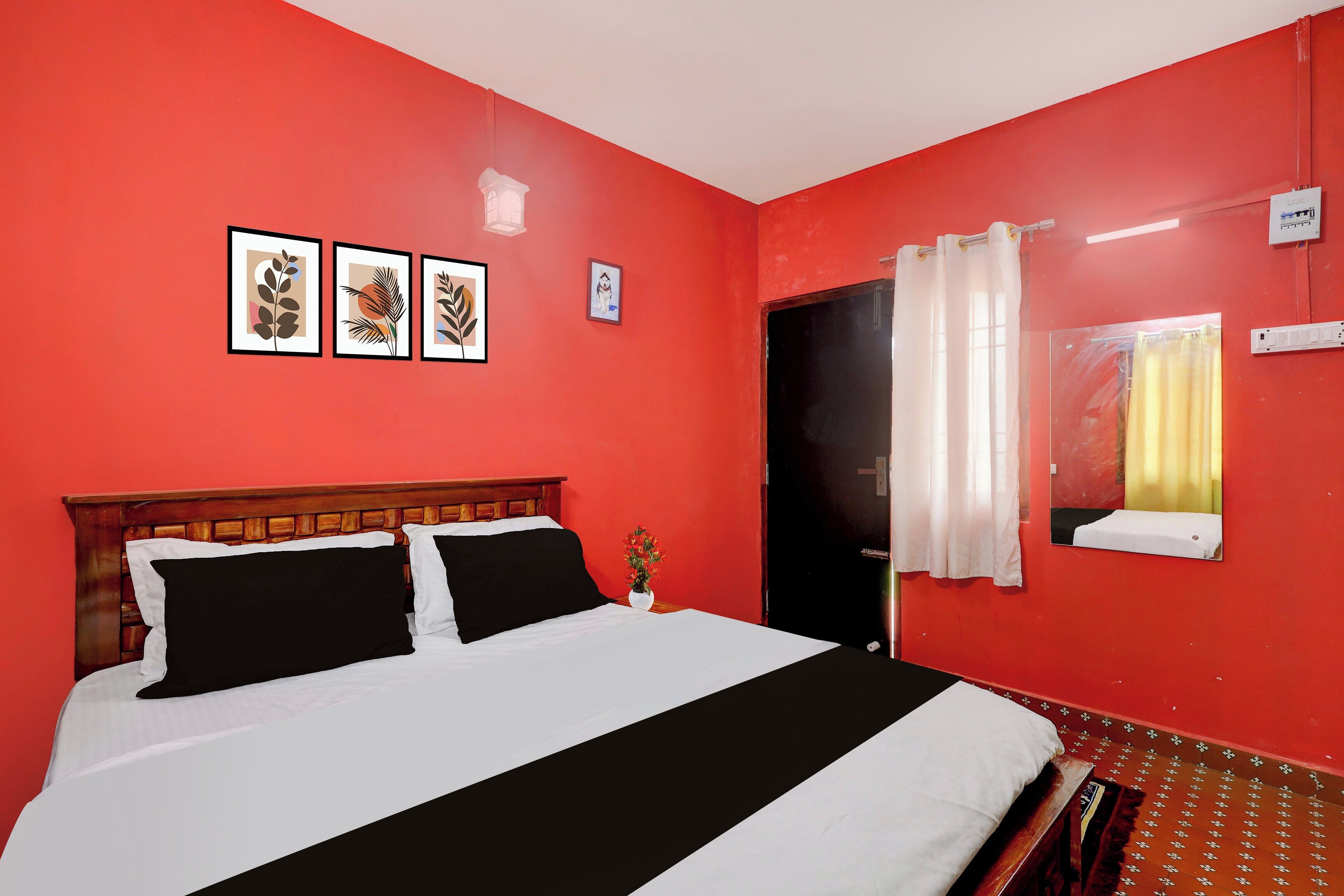 A room with a bed, a door, a window with curtains, and wall-mounted artwork.