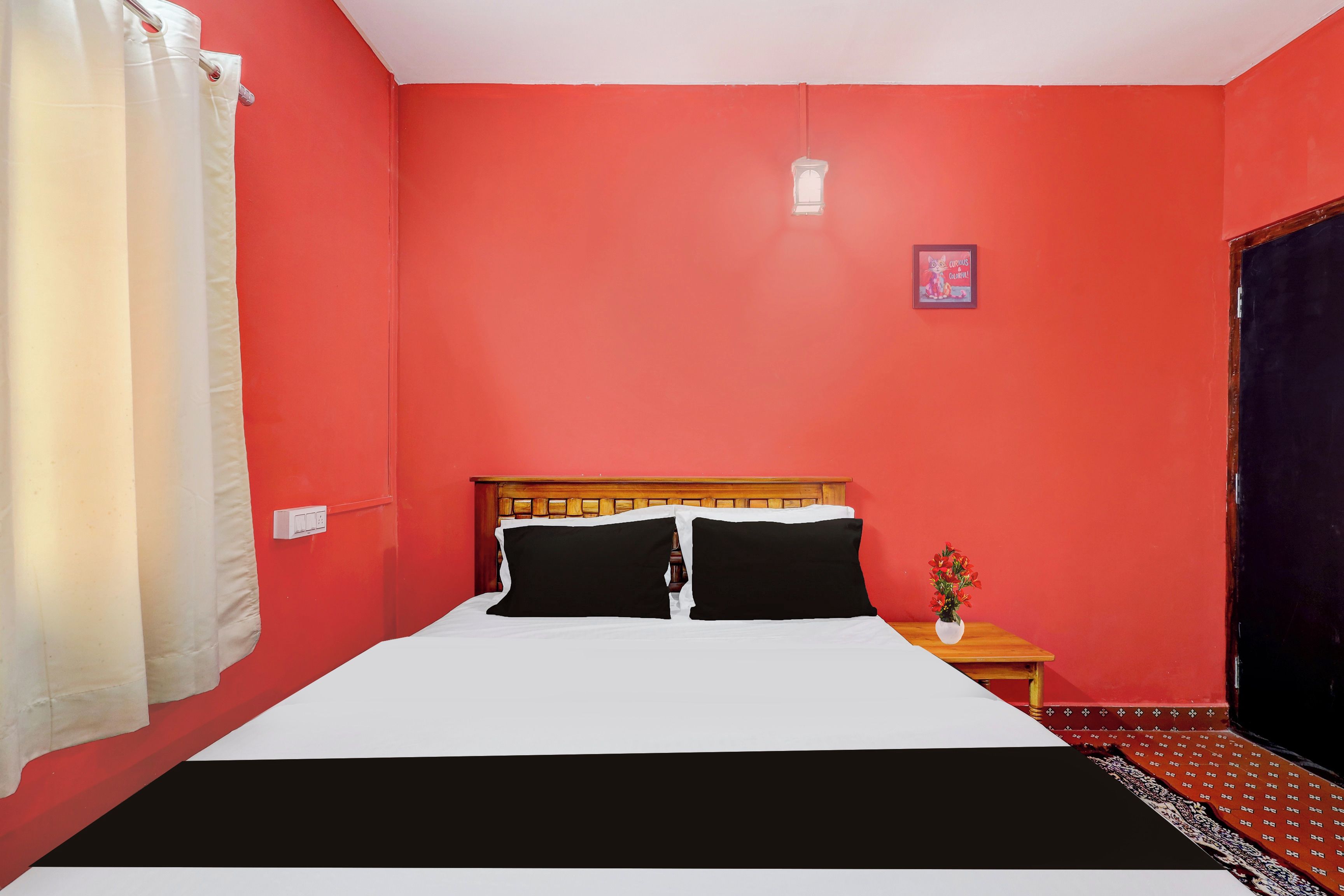 Una habitación con una cama, una mesita de noche, un reloj de pared y una ventana con cortinas.