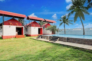 A resort with multiple red-roofed buildings, a swimming pool, and palm trees.