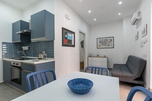 Une cuisine compacte dotée d’appareils électroménagers modernes, un coin repas avec une table et des chaises, et un canapé.