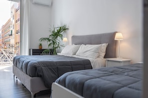 Ein modernes Schlafzimmer mit zwei Betten, einer Topfpflanze und Balkonblick.