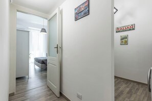 Ein Flur mit einem Bett im Hintergrund, einer Tür und einer Wand mit dem Schriftzug 'Authentic Italian Cuisine'.