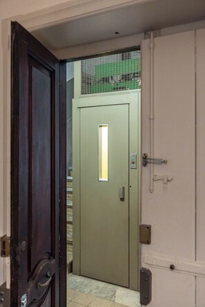 Eine geschlossene Tür mit kleinem Fenster und einer Steuerung, die zu einer Treppe führt.