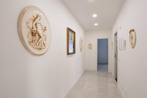 Un couloir aux murs blancs et au sol carrelé, agrémenté de plusieurs éléments décoratifs de forme ovale fixés aux murs.
