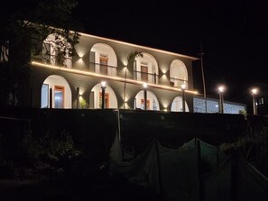 Ein Gebäude mit mehreren Rundbogenfenstern und Balkonen, beleuchtet durch Außenbeleuchtung.