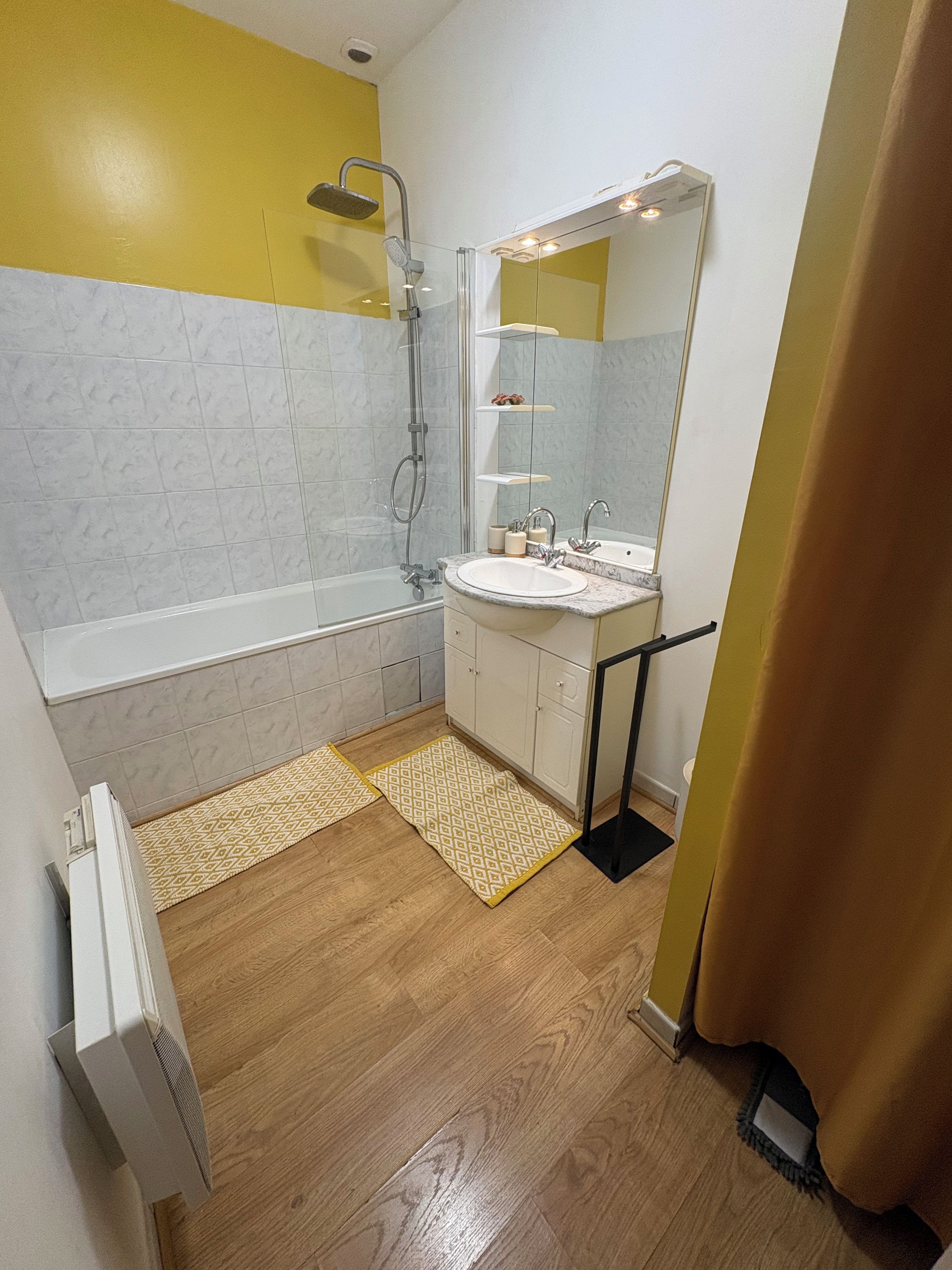 A bathroom with a bathtub, a shower, a sink, and a mirror.