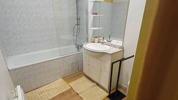 A bathroom with a bathtub, a shower, a sink, and a mirror.