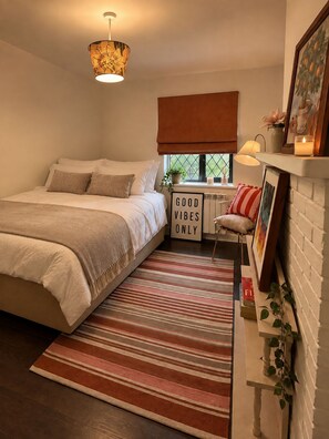 A bedroom with a bed, a bedside table with a lamp, a window with a view, and a sign that reads 'GOOD VIBES ONLY'. - Stunning detached 3-bed Country House (Plaistow)