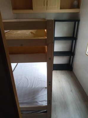 Ein Stockbett mit Holzrahmen und einer weißen Matratze im unteren Bett.