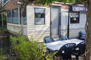 A mobile home with a covered patio area, a table, and chairs. - Gezinsvakantie in de Drentse natuur | Stacaravan (Wijster)