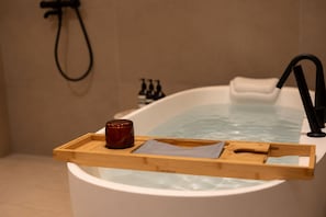 Una bañera con una bandeja de madera que sostiene una vela y una toalla.
