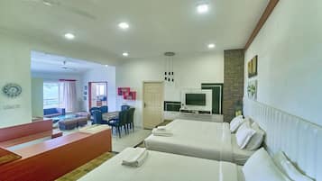A hotel room with two beds, a desk, a television, and a view of the outside.