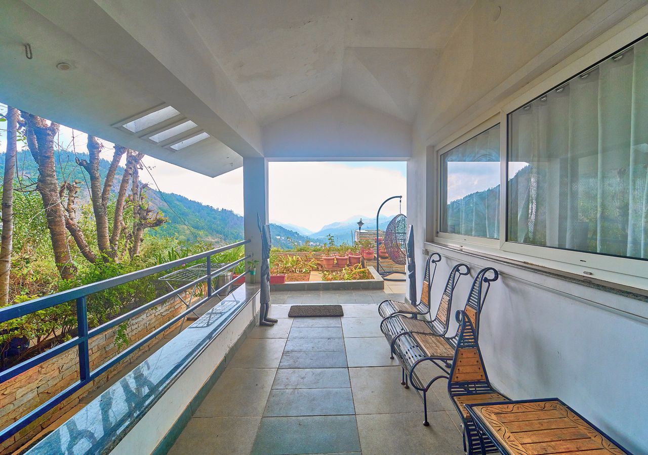 Un balcon donnant sur un paysage montagneux, avec un banc et une balustrade.
