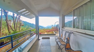 Un balcon donnant sur un paysage montagneux, avec un banc et une balustrade.