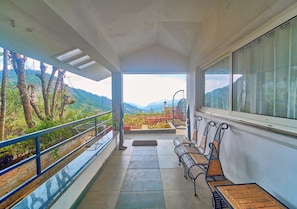 A balcony with a view of a mountainous landscape, a bench, and a railing. - Cozy Retreat Inn Ooty by VOYE HOMES (Coonoor)