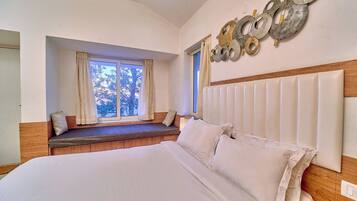 A bedroom with a large bed, a window seat, and a decorative wall piece.