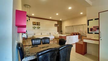 A compact living space with a dining area, a kitchenette, and a seating area with a sofa and a coffee table.