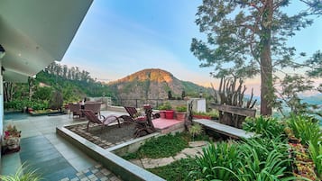 Un patio al aire libre con un espacio de estar, un banco de madera y diversas plantas en macetas.