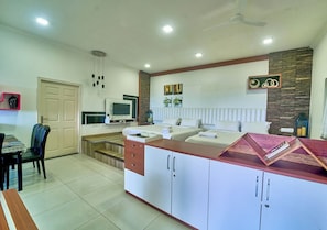 A modern kitchen with a dining area, a TV, and a built-in cabinet. - Cozy Retreat Inn Ooty by VOYE HOMES (Coonoor)