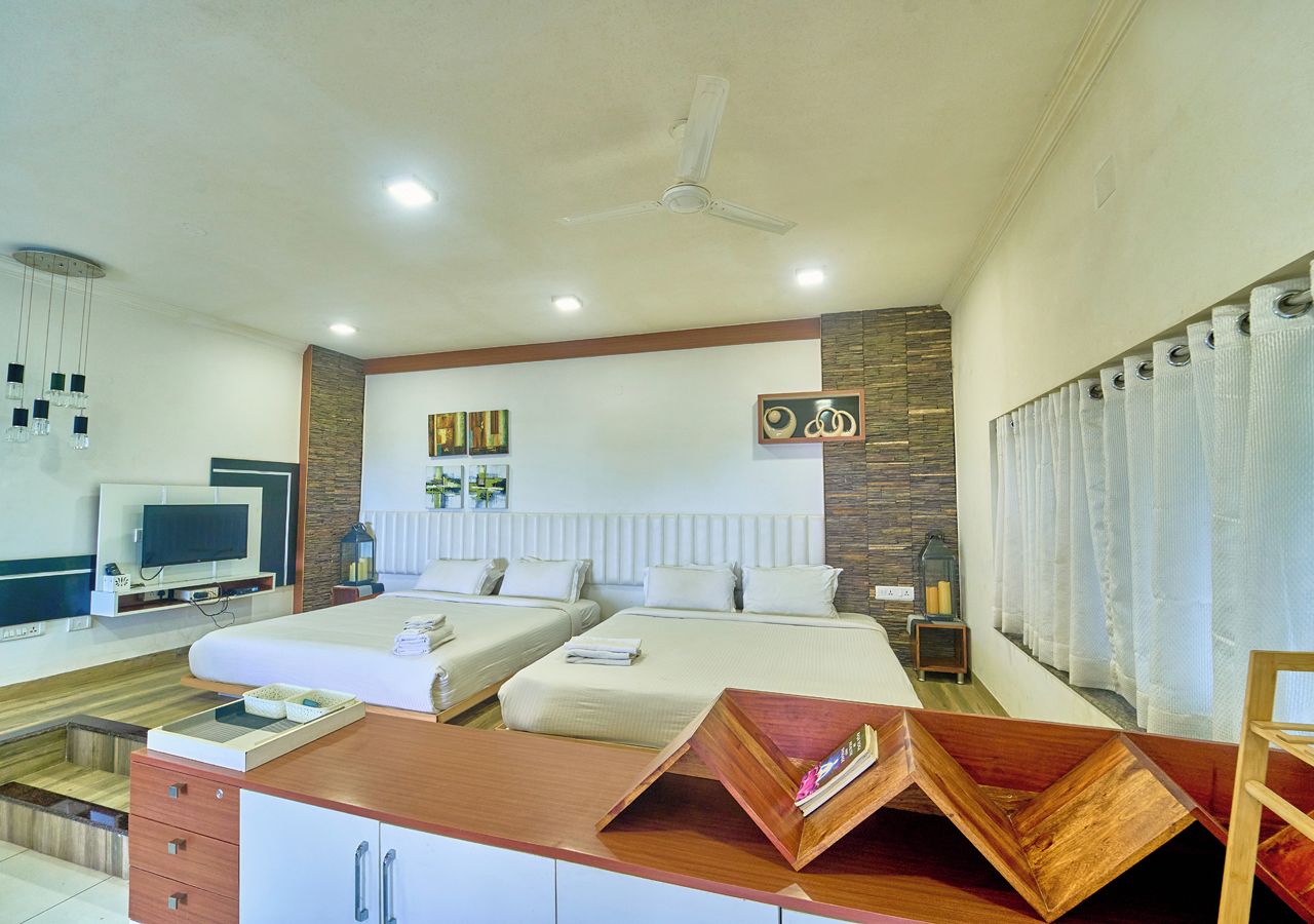 A hotel room with two beds, a desk with a flat-screen TV, and a ceiling fan.