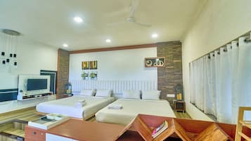 A hotel room with two beds, a desk with a flat-screen TV, and a ceiling fan.