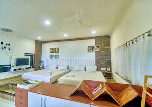 A hotel room with two beds, a desk with a flat-screen TV, and a ceiling fan. - Cozy Retreat Inn Ooty by VOYE HOMES (Coonoor)