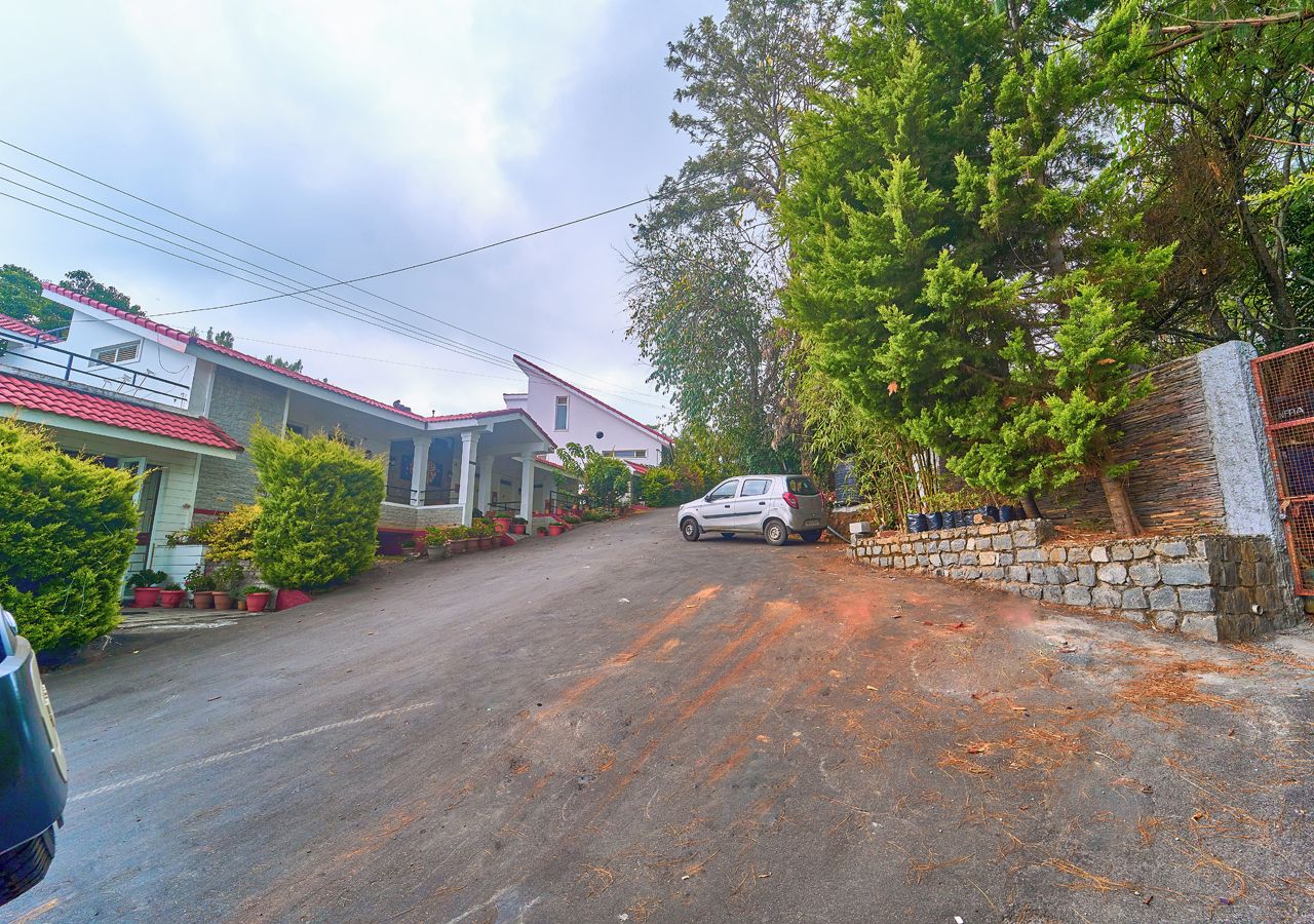 Une rue résidentielle bordée de maisons, avec une voiture garée et un mur en pierre.
