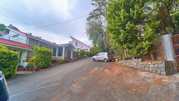 Une rue résidentielle bordée de maisons, avec une voiture garée et un mur en pierre.