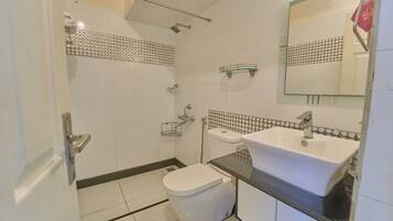 Un baño con inodoro, lavamanos, ducha y espejo.