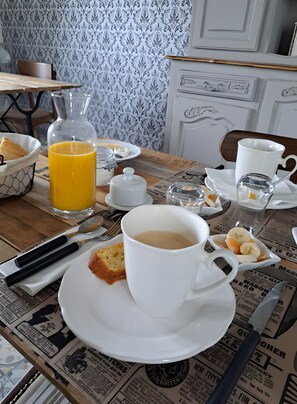 Et morgenbord med en kop kaffe, et glas appelsinjuice, en tallerken med ristet brød og smør, samt en avis.