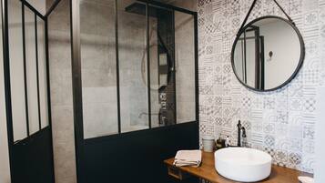Une salle de bain avec un grand miroir, un lavabo rond et des carreaux décorés.