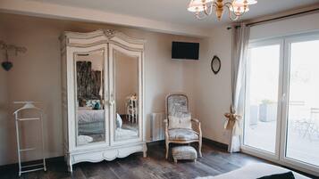 Une pièce avec un grand miroir, une chaise, un lit, un radiateur et une fenêtre avec des rideaux.