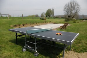 A portable ping pong table with wheels, set up on a grassy field with a small seating area and trees in the background. - Bed and Breakfast 'Chambres Azélice' with Shared Terrace, Shared Garden and Wi-Fi (Féron)