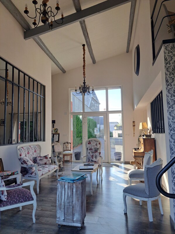 Una habitación amplia con techo alto, un candelabro y un gran ventanal con vistas al exterior.