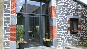 Un bâtiment doté d’une façade en pierre, de grandes portes vitrées et de plantes en pot au niveau du rez-de-chaussée.
