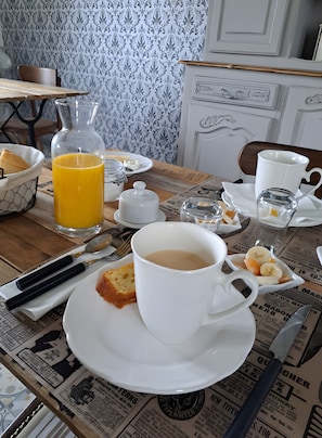 Et morgenbord med en kop kaffe, et glas appelsinjuice, en tallerken med ristet brød og smør, samt en avis.