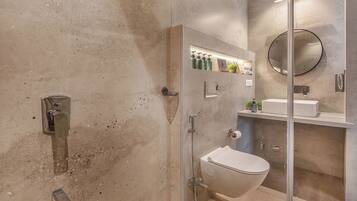 A modern bathroom with a glass-enclosed shower, a toilet, and a sink with a mirror above.