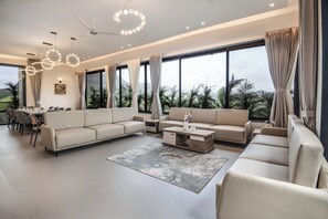 Un salon moderne comprenant un canapé d’angle, une table basse et un coin repas avec des chaises et une table.