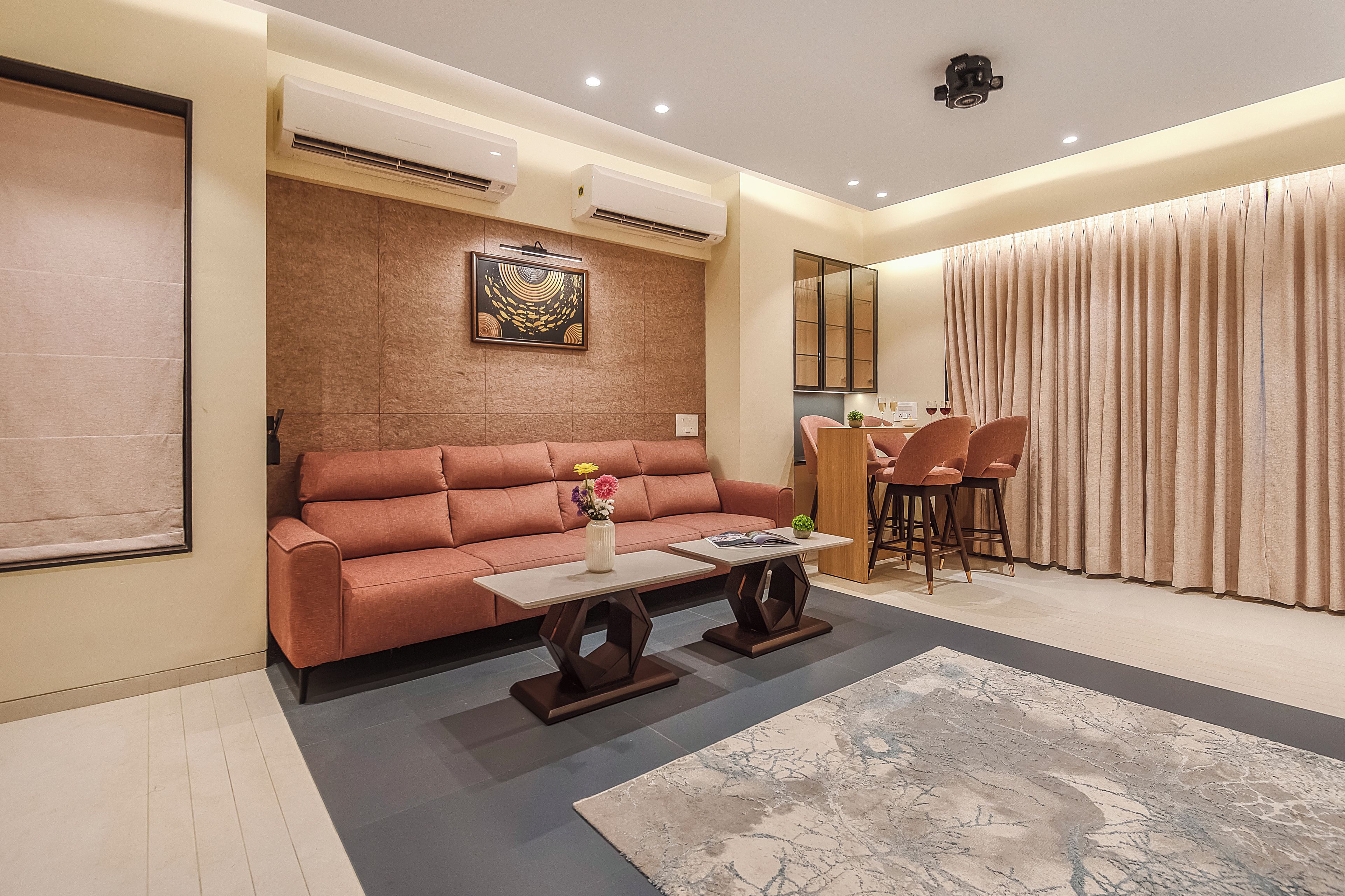 A modern living room with a sofa, a coffee table, and a dining area with chairs.