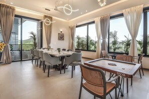 Un espace repas comprenant une table de billard, plusieurs chaises et de grandes fenêtres donnant sur l’extérieur.