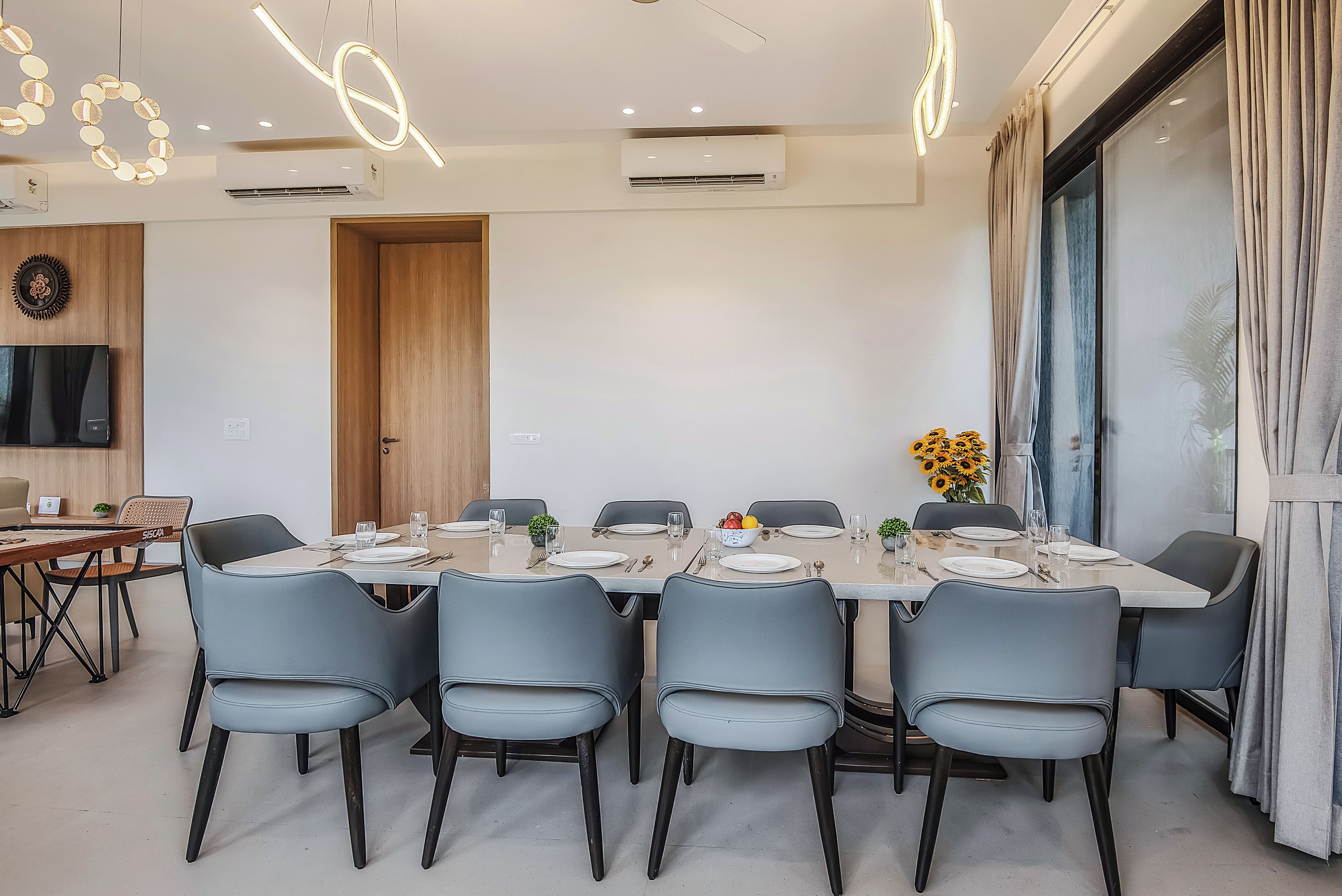 A modern dining room with a long table set for six, surrounded by six chairs.