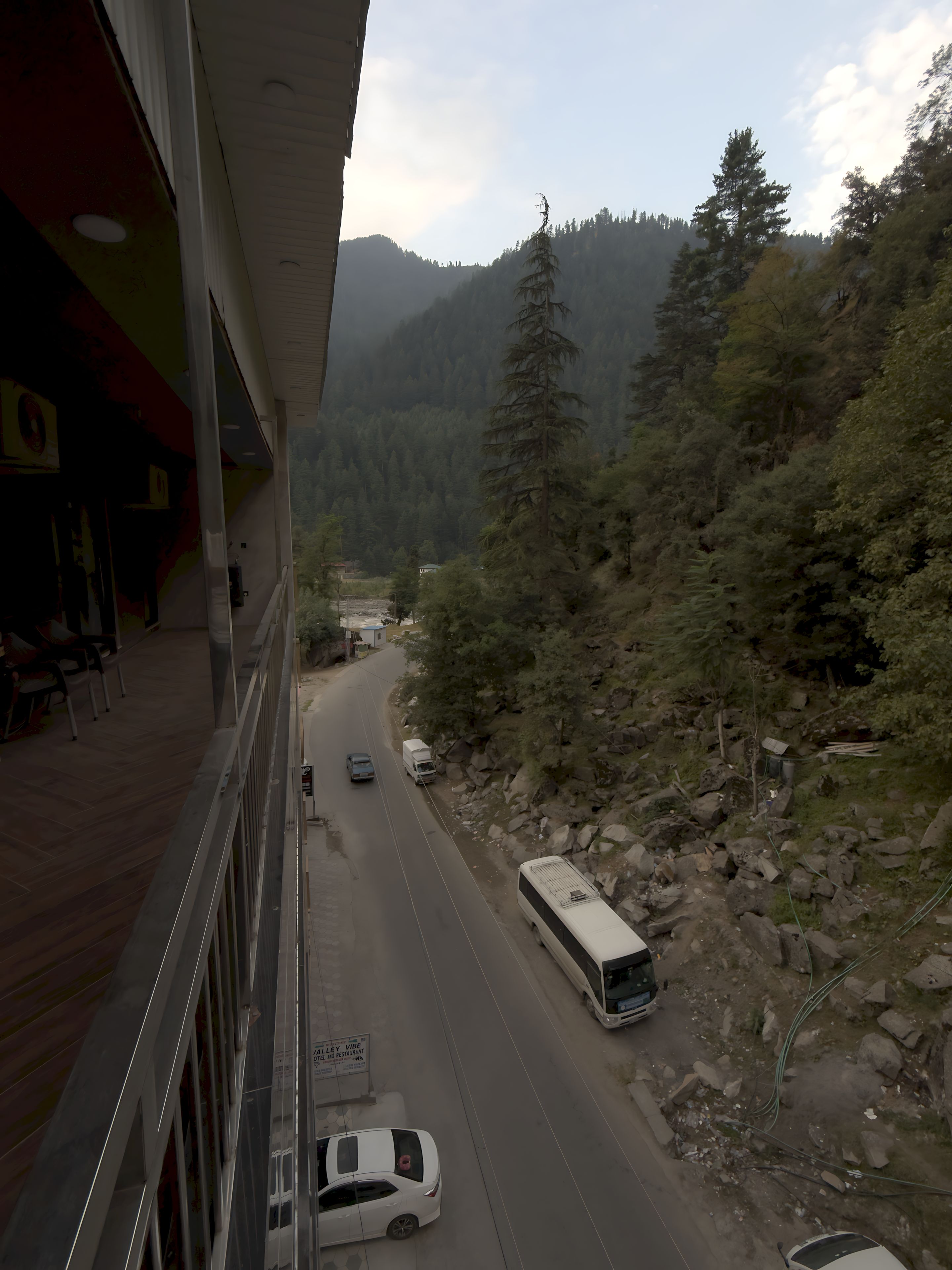 A road with vehicles, a bus, and a mountainous landscape.