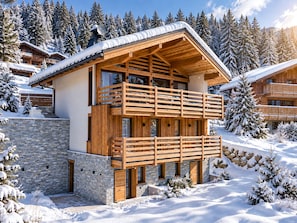 A wooden chalet with a stone foundation, a balcony, and a view of snow-covered trees. - Chalet Mara (Les Houches)