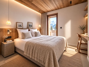 A bedroom with a bed, bedside tables, a desk, and a view of mountains. - Chalet Mara (Les Houches)