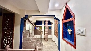 A staircase with a blue accent wall, a decorative pillar, and a wall-mounted shelf with a vase.
