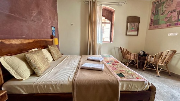 Una habitación con una cama, una ventana con cortinas, una silla y una pared con un cuadro enmarcado.